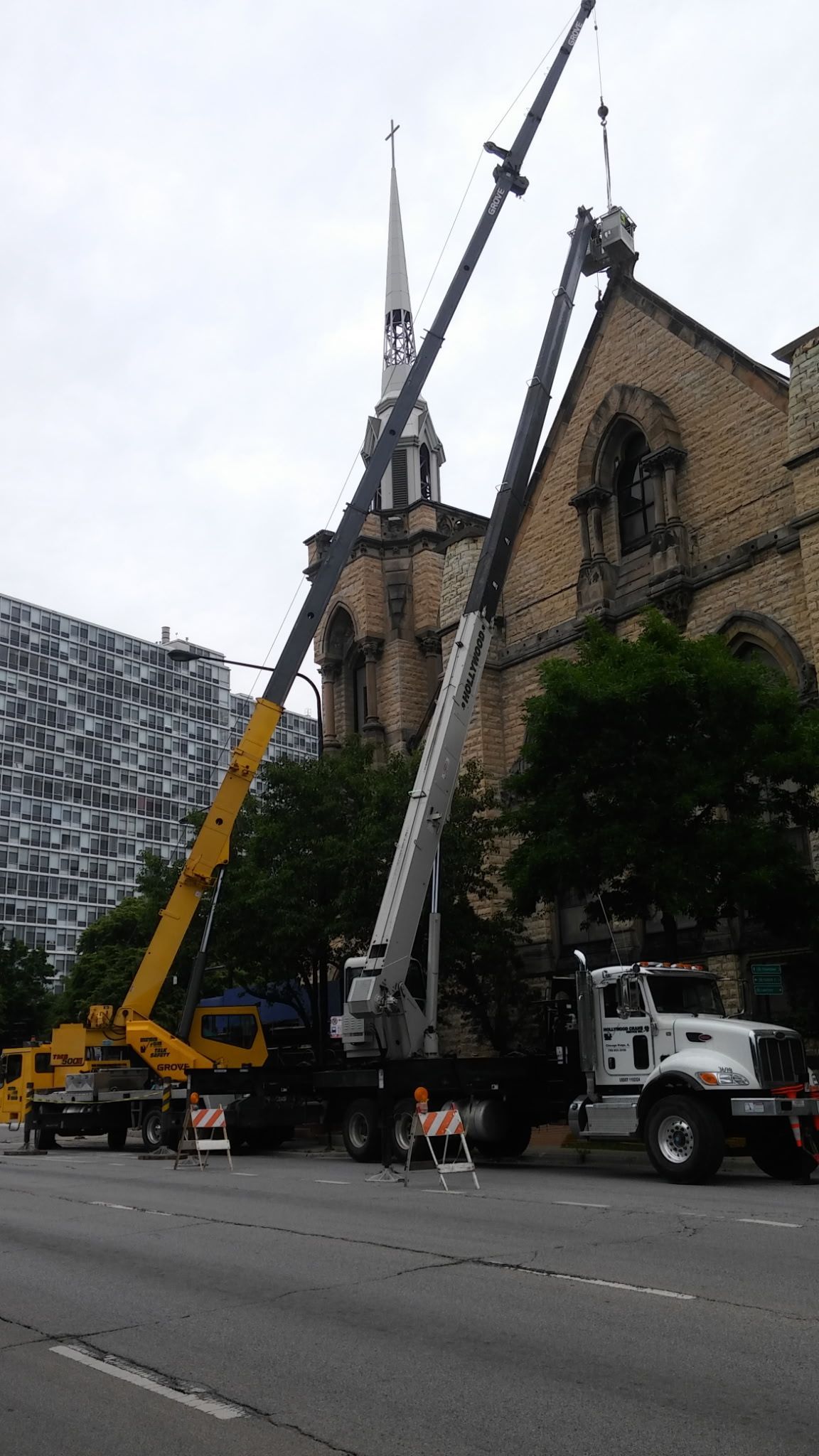 A truck with a crane attached to it is parked in front of a church.