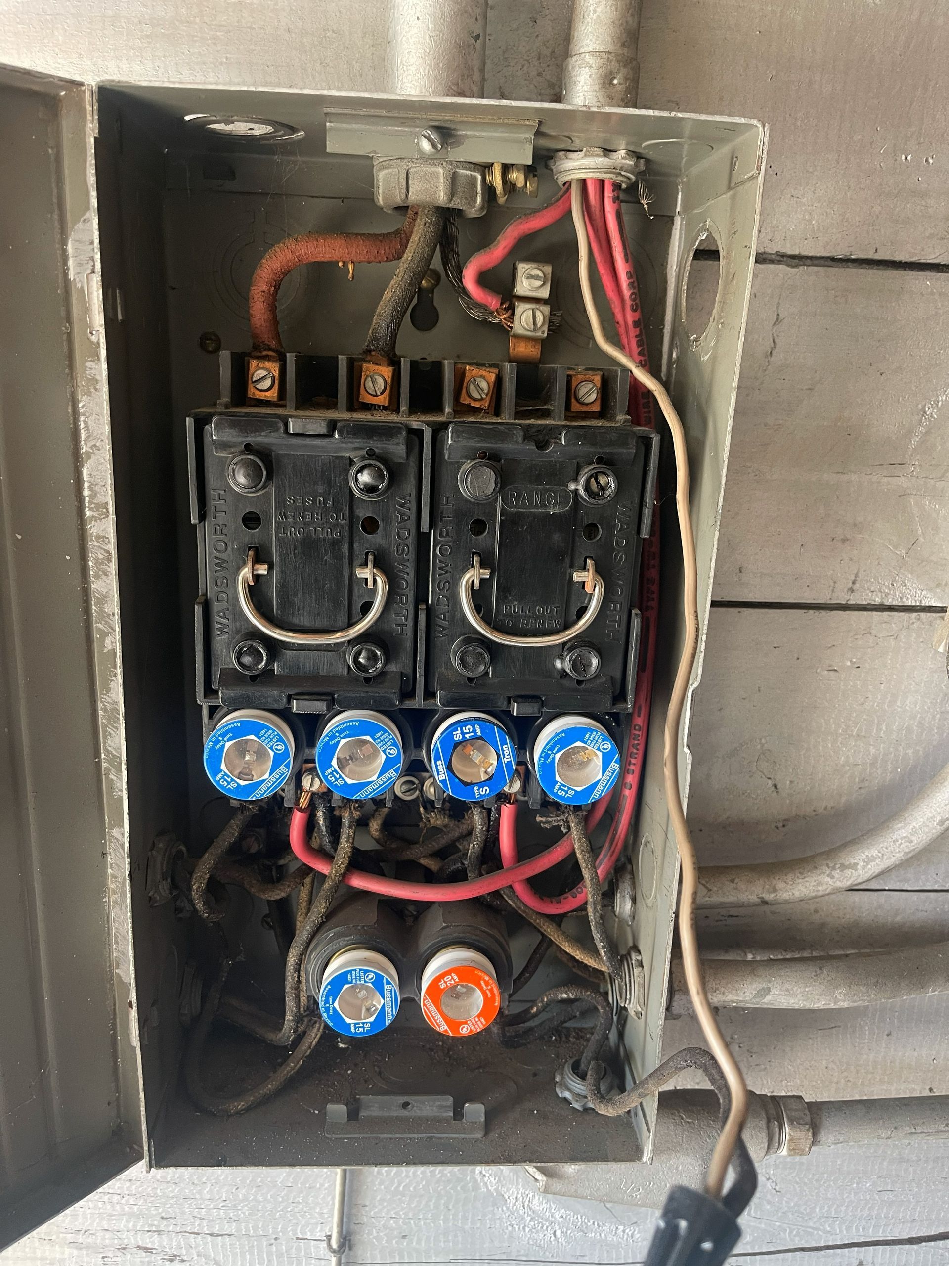 Open electrical panel with fuses, wires, and switches.