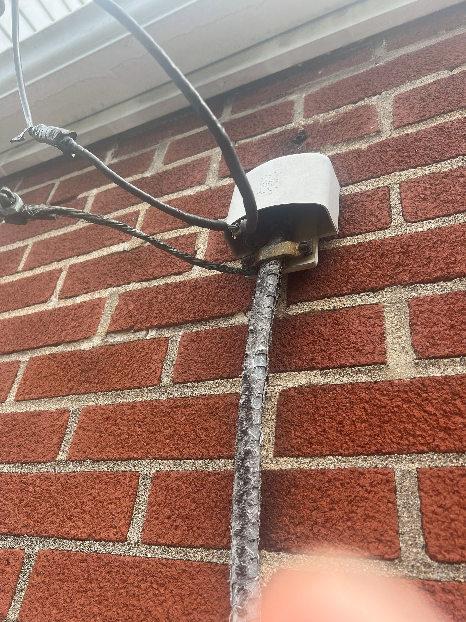 White electrical fixture on brick wall with multiple wires attached.