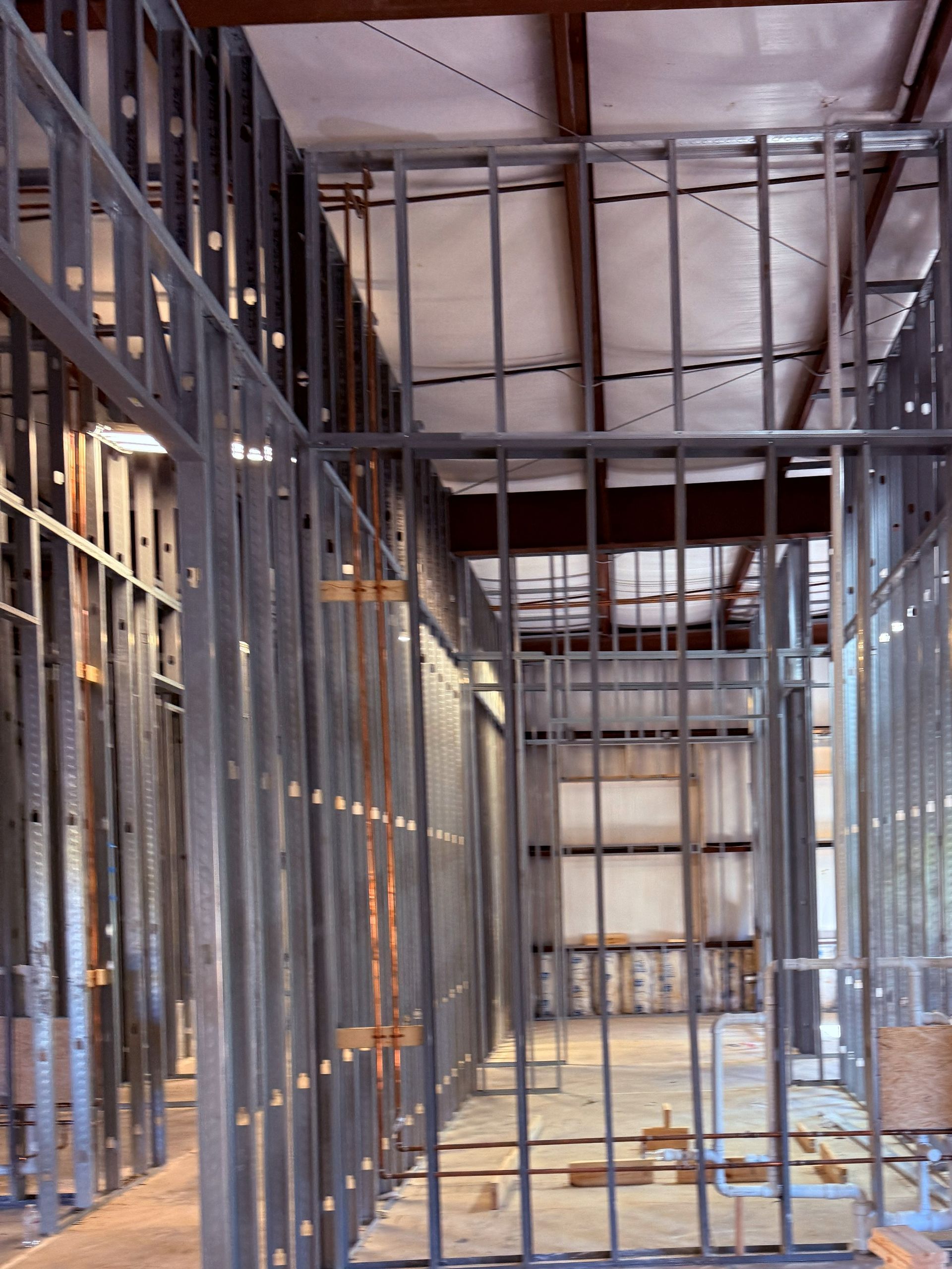 Interior view of a building under construction, showing steel stud framing for walls and ceiling.