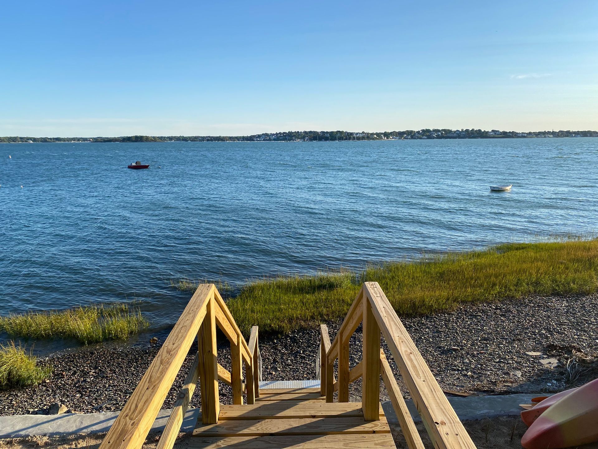 A wooden dock leading to a body of water with a boat in the distance.