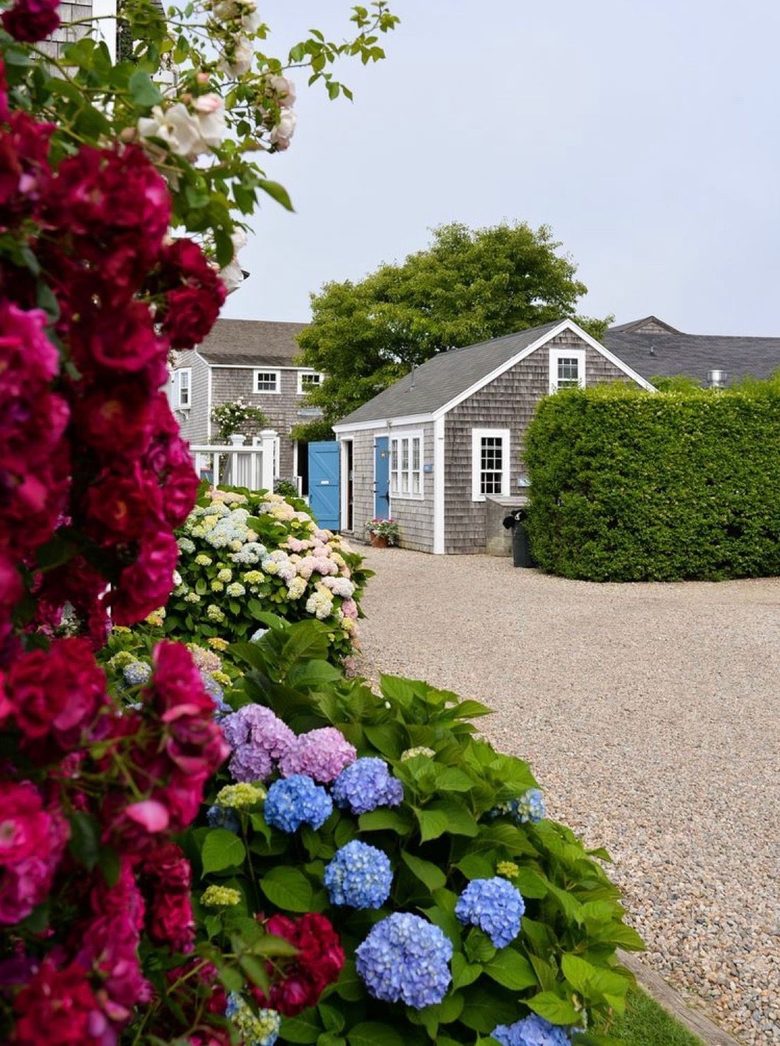 A house with a gravel driveway and flowers in front of it