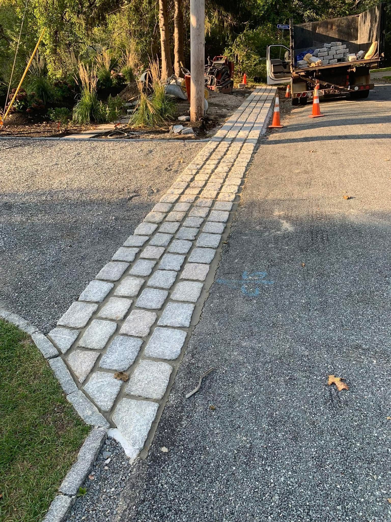 A stone walkway is being built in a gravel driveway.