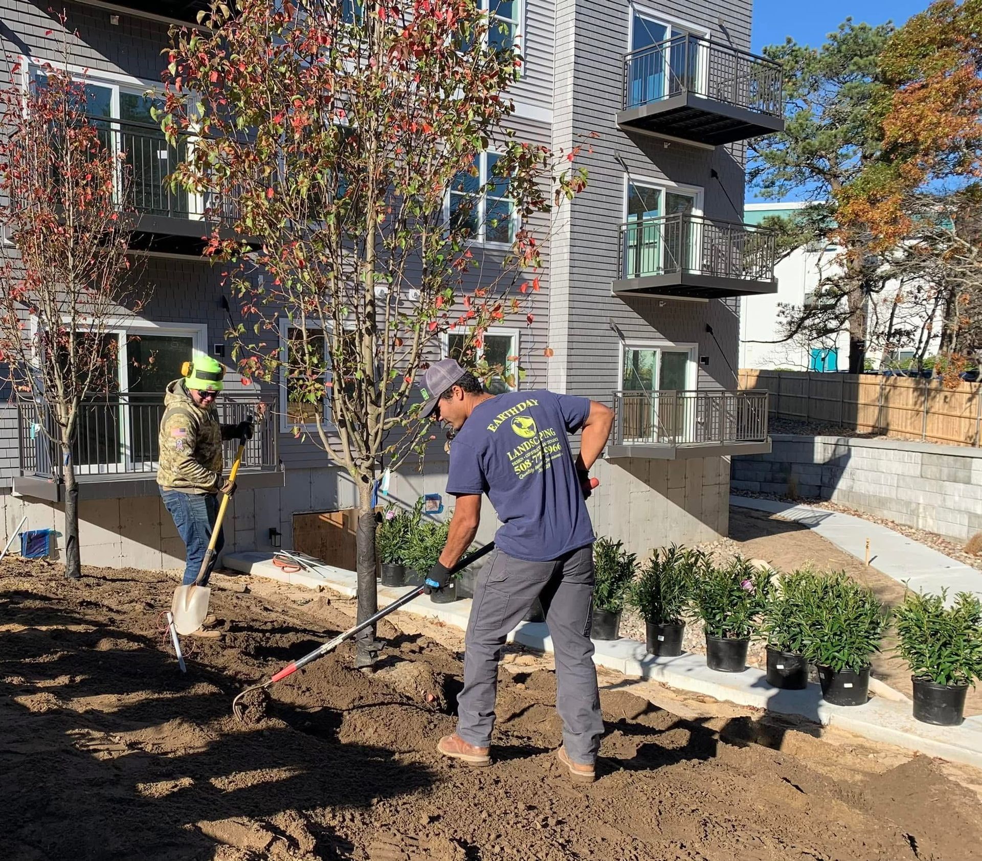 Two men are digging in the dirt in front of a building.