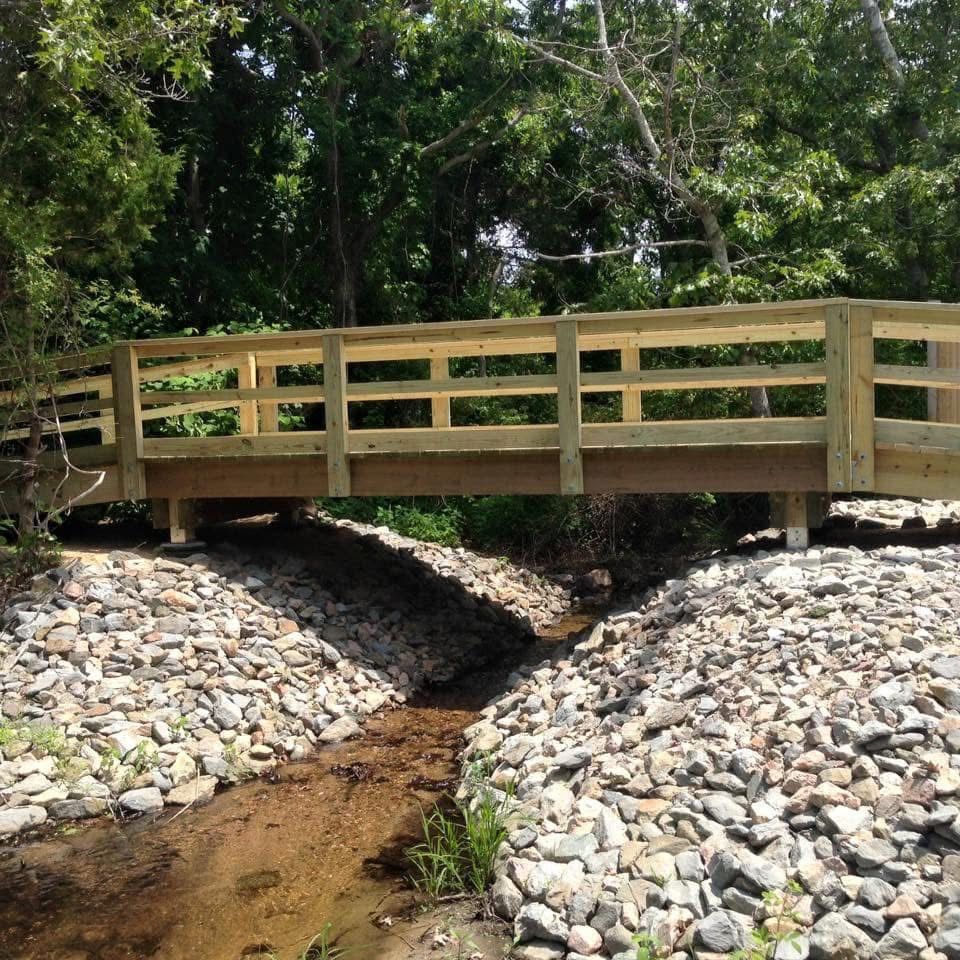 A wooden bridge over a stream surrounded by rocks