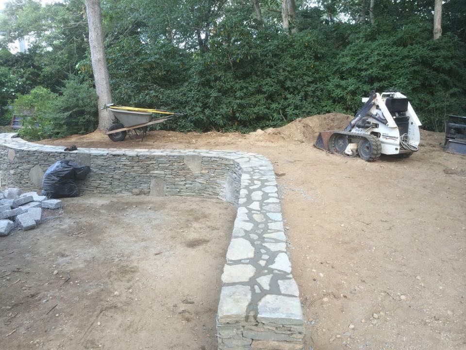 A bulldozer is parked next to a stone wall