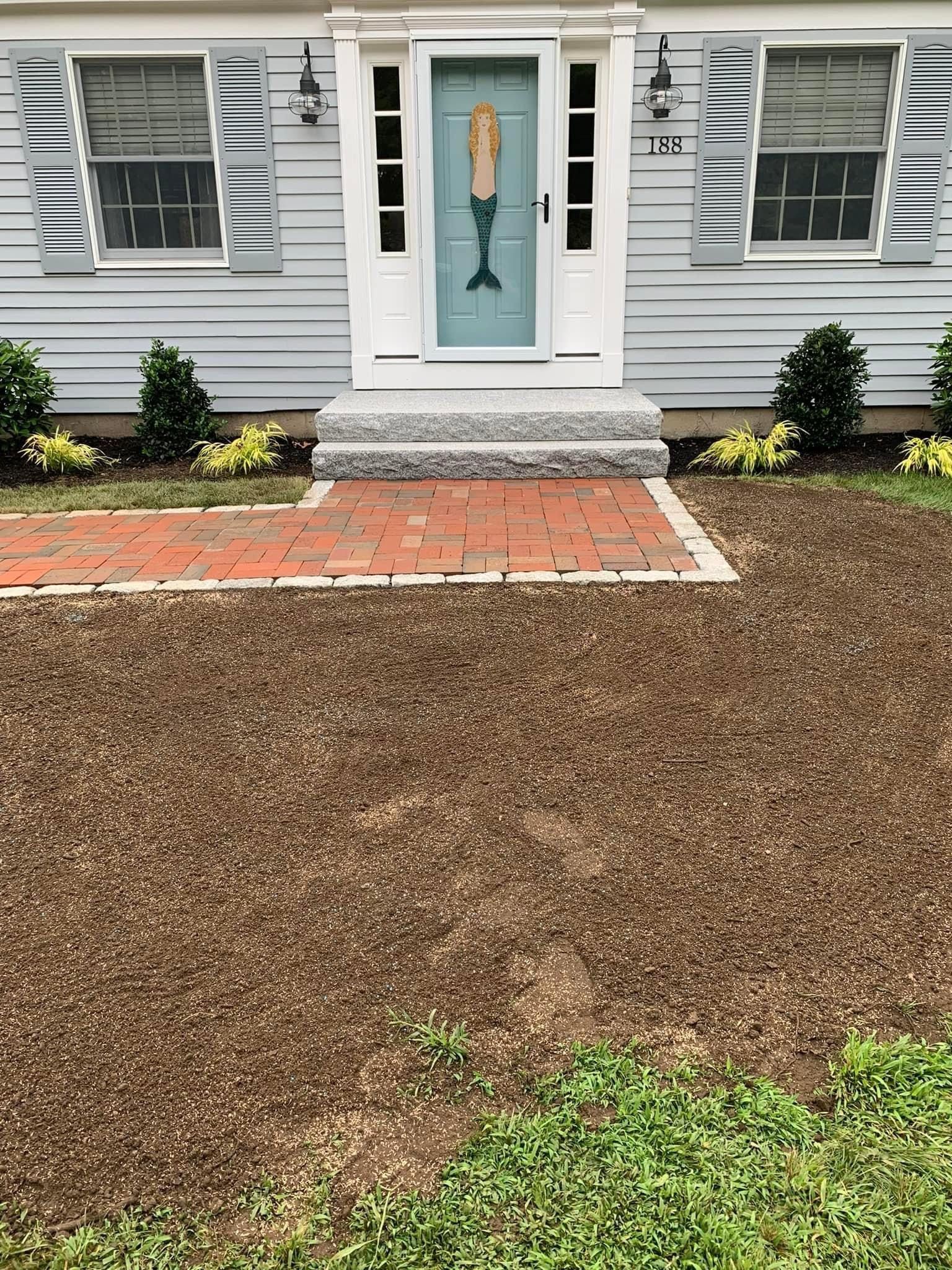 The front of a house with a mermaid door and a brick walkway.