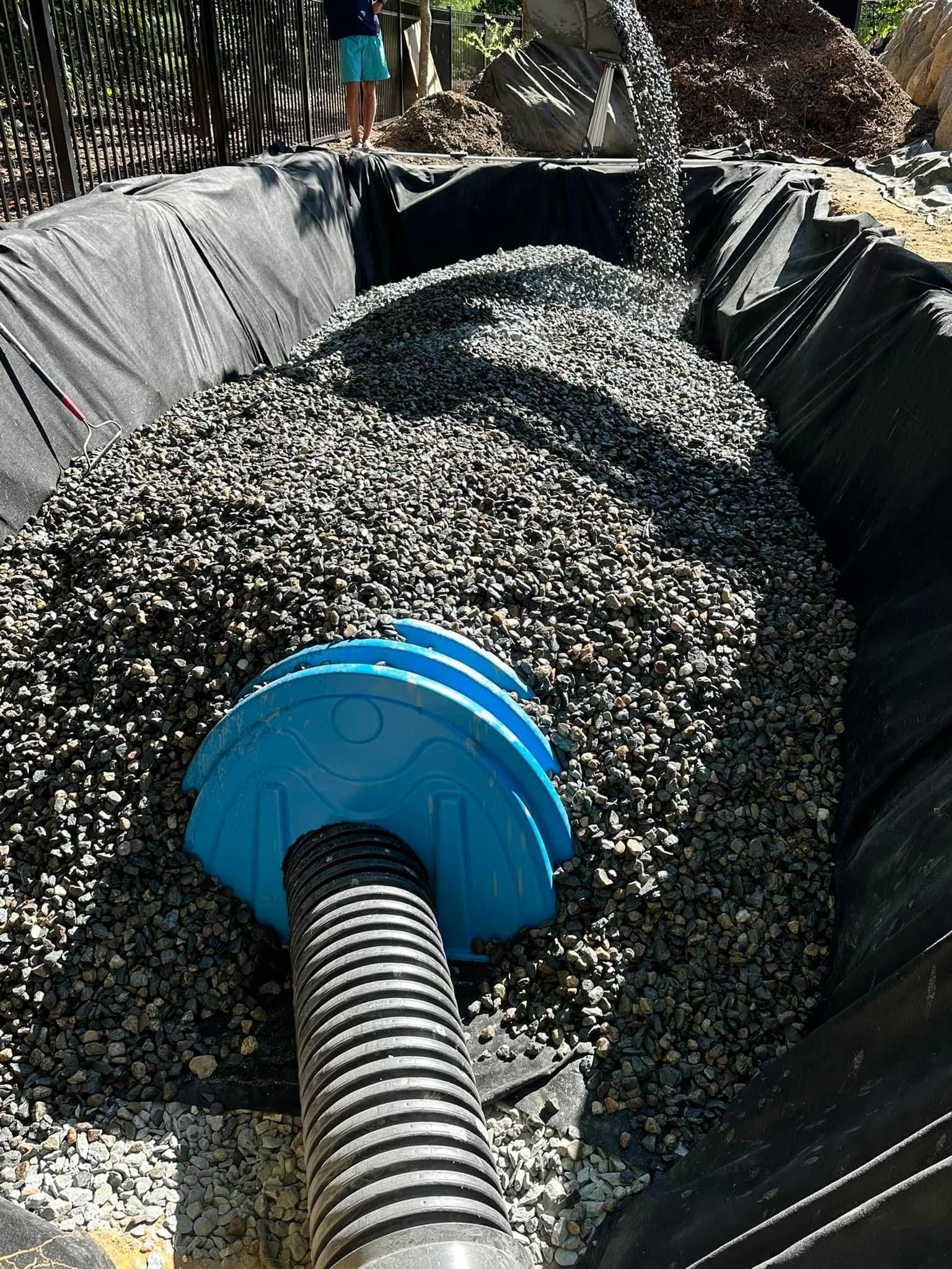 A vacuum hose is being used to pump gravel into a pond.
