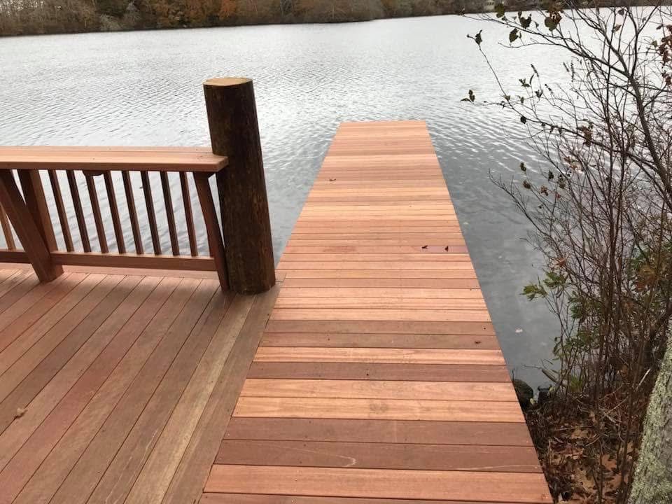 A wooden dock leading to a lake with a wooden railing