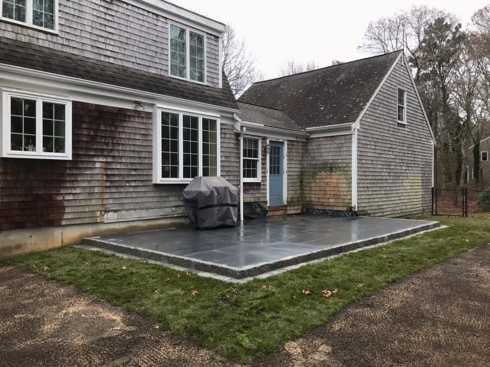 A large house with a patio and a grill in front of it.