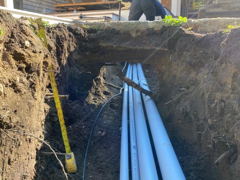 A man is working in a trench with a yellow tape measure