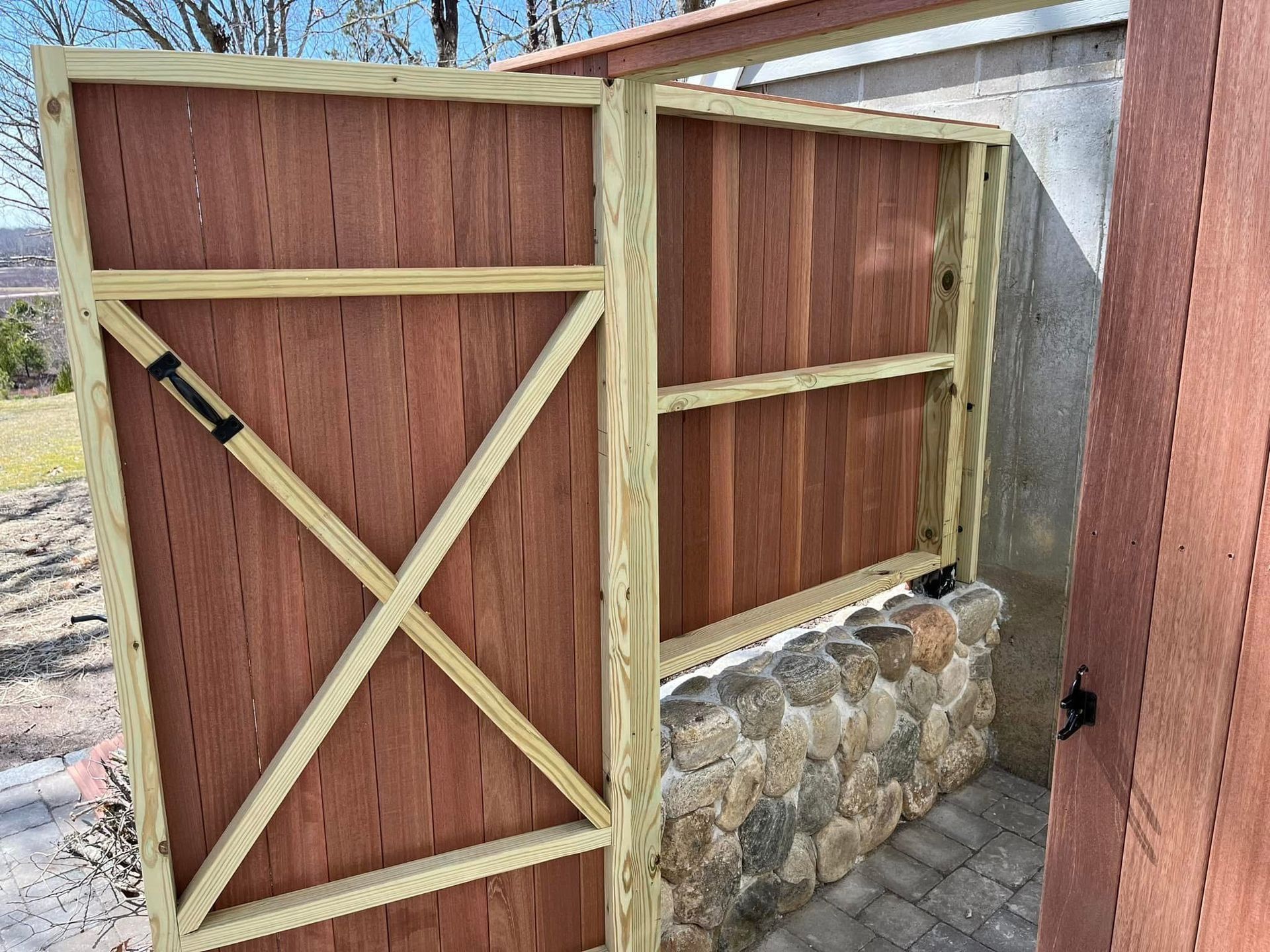 A wooden fence is sitting next to a stone wall.