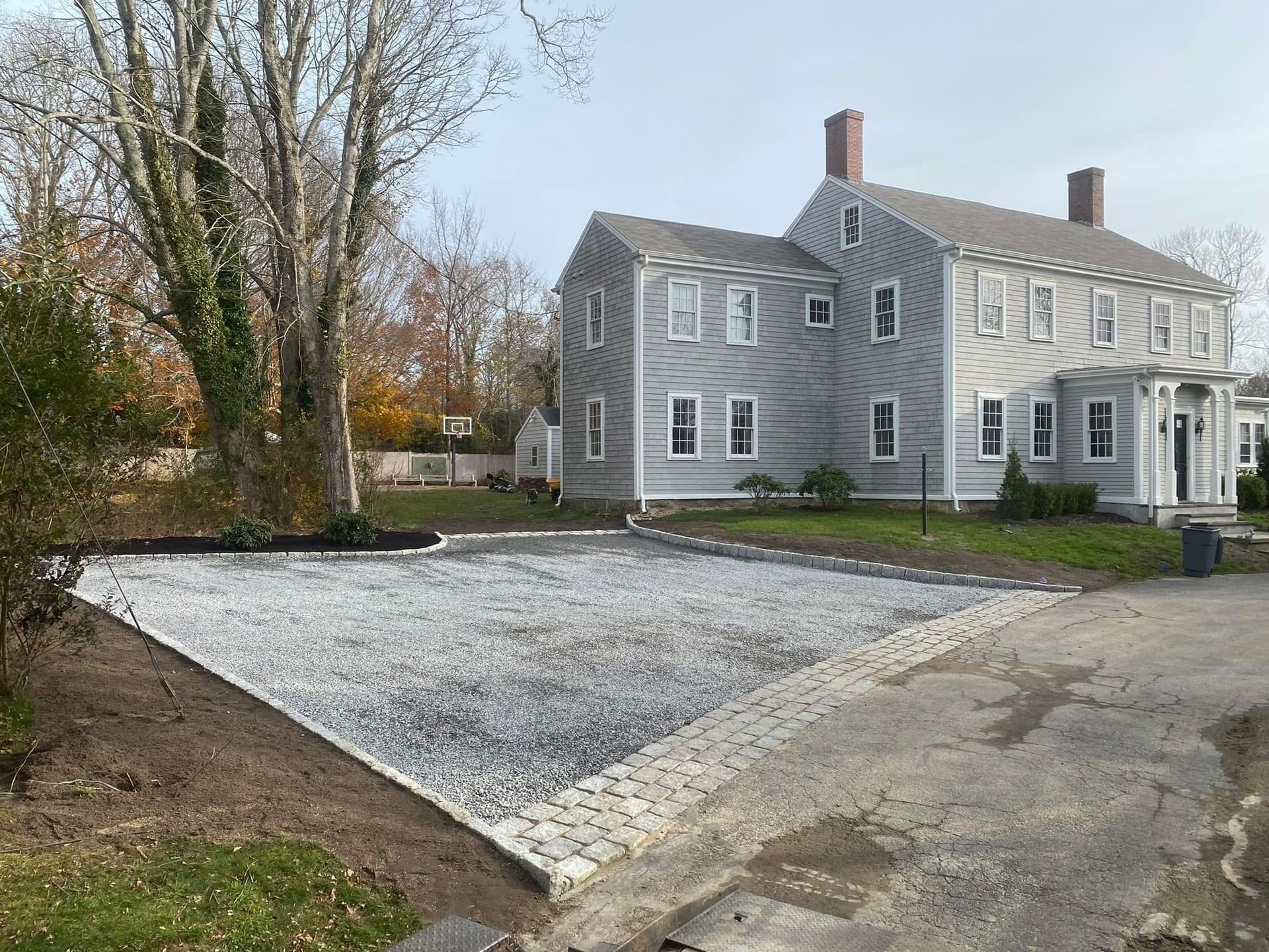 A large house with a gravel driveway in front of it.