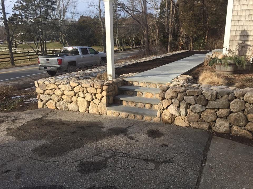 A white truck is parked in front of a stone wall