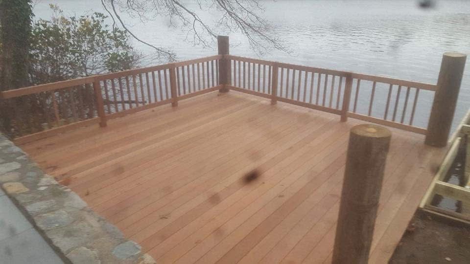 A wooden deck with a railing overlooking a body of water.