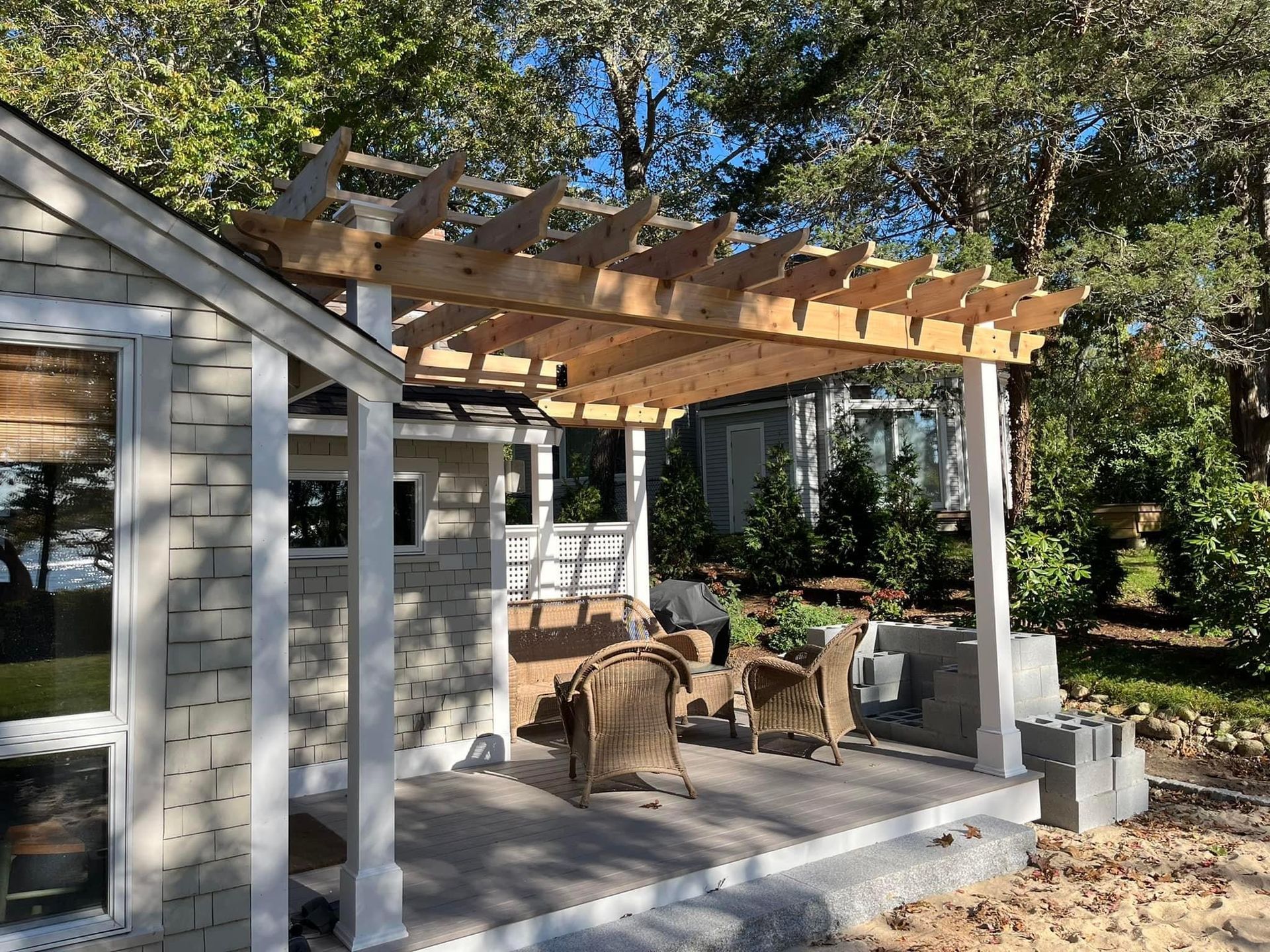 A wooden pergola is sitting on top of a patio next to a house.