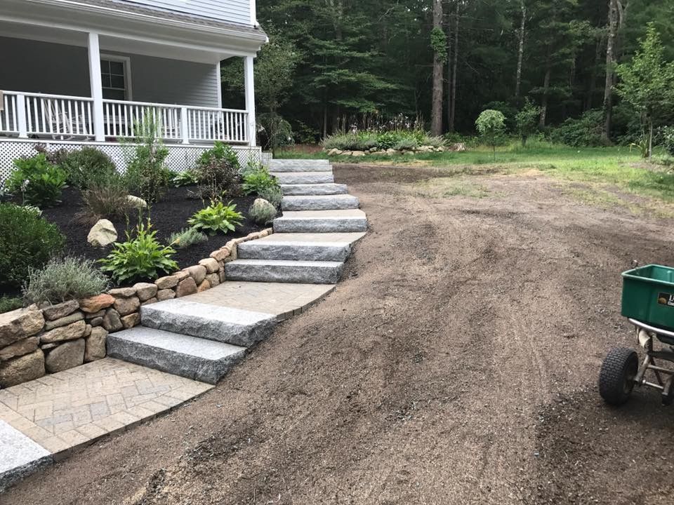 A house with stairs and a wheelbarrow in front of it.