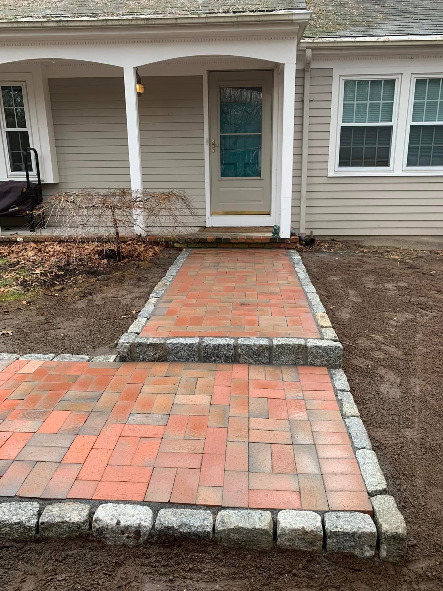 A brick walkway leading to the front door of a house.
