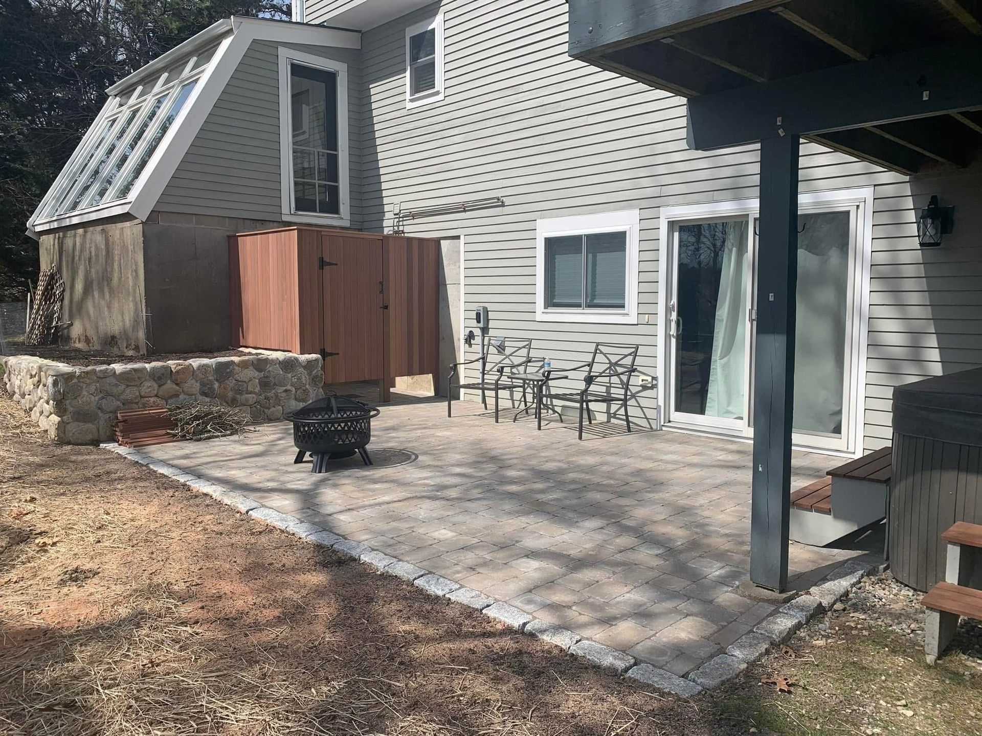 The backyard of a house with a patio and a fire pit.