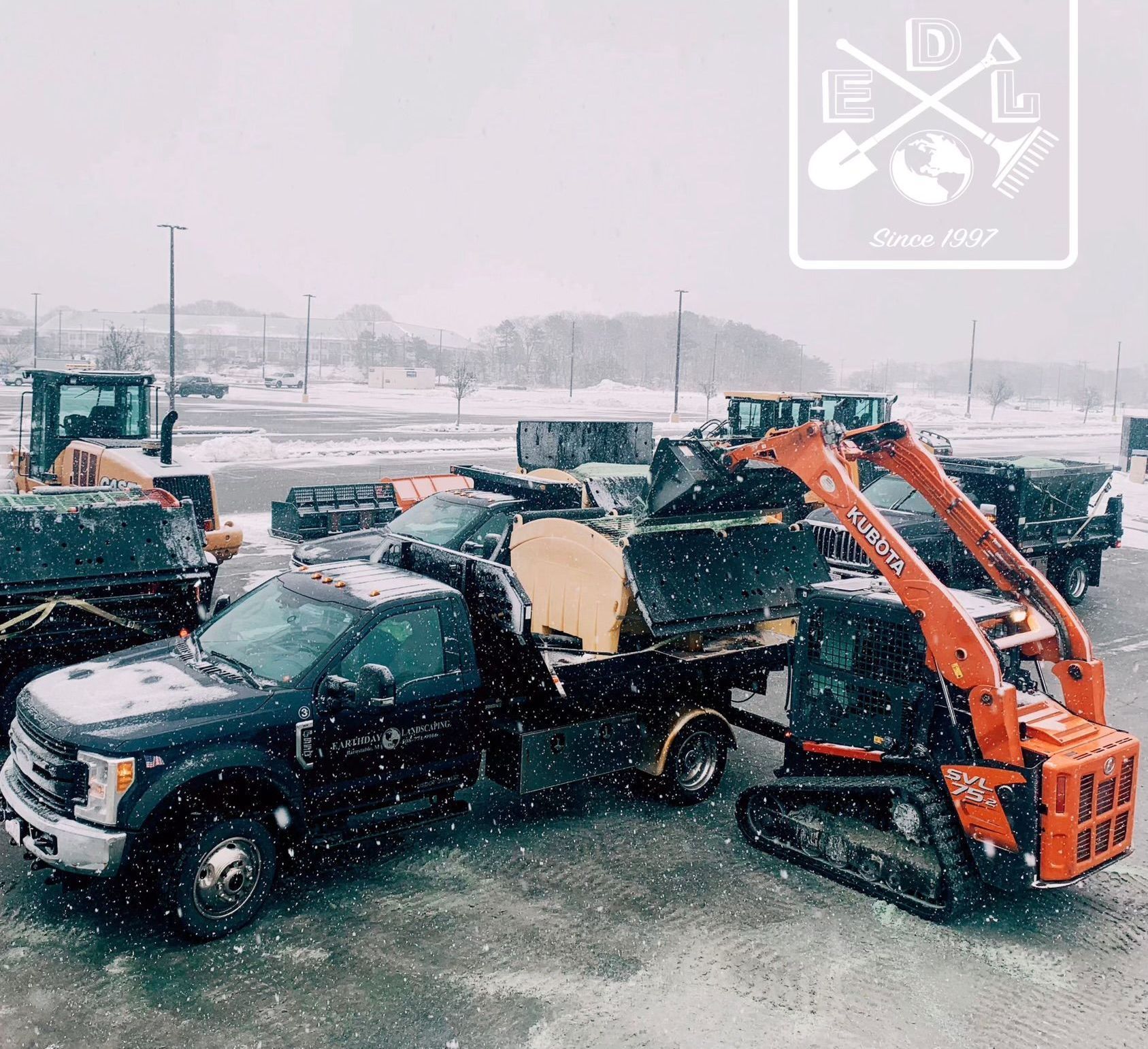 A group of trucks and tractors are parked in the snow.