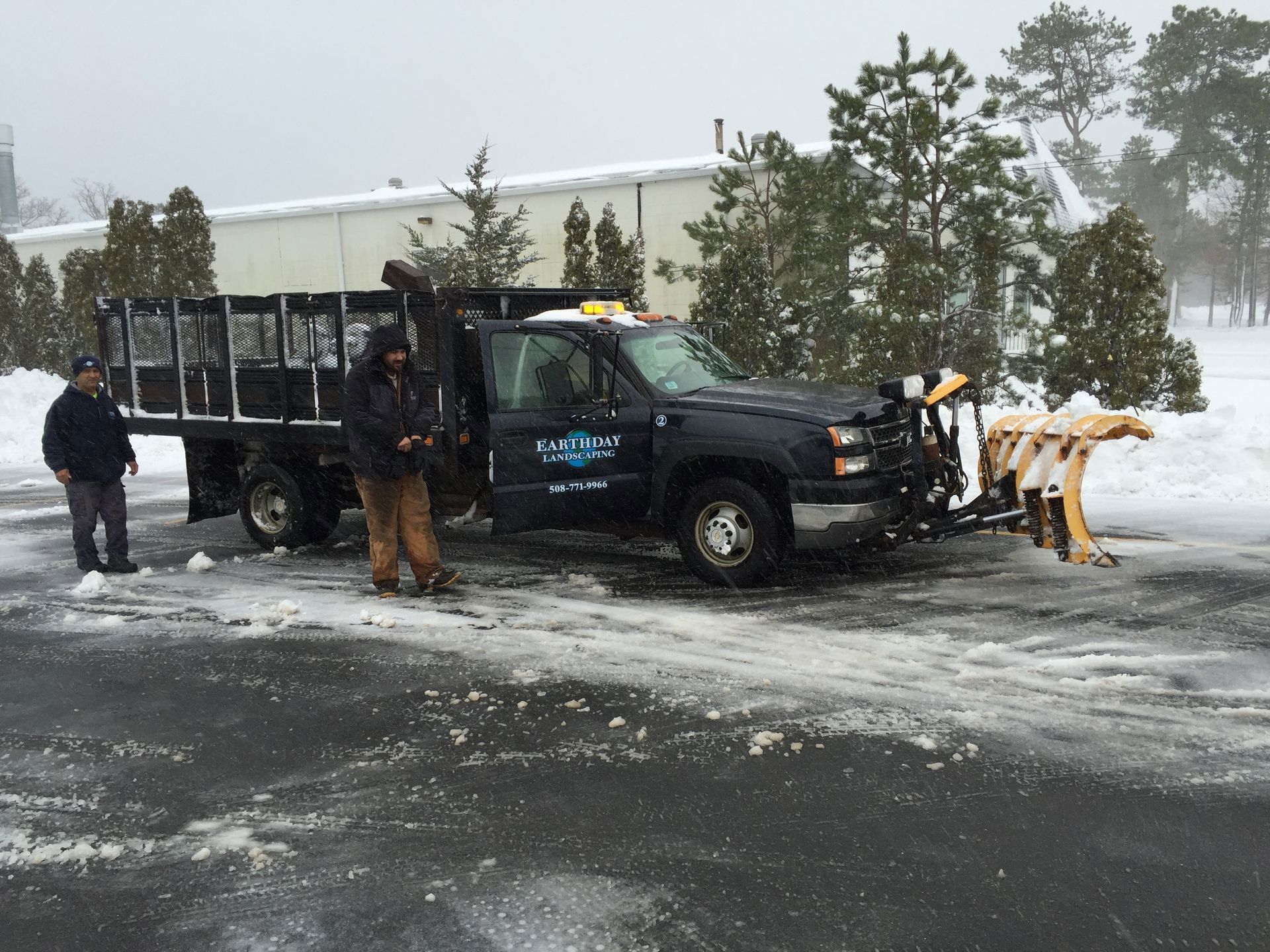 A snow plow is parked in a parking lot