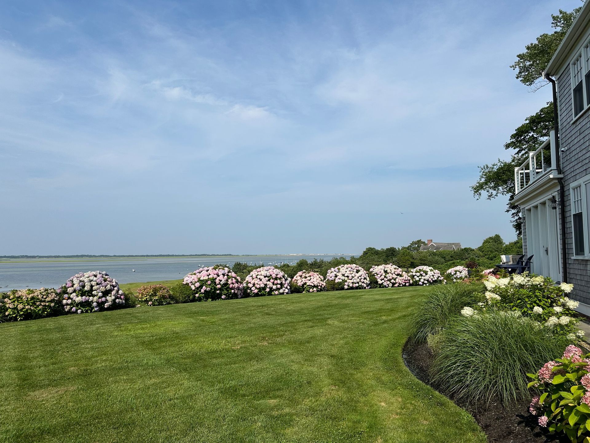 A large house with a lush green lawn and flowers in front of it.