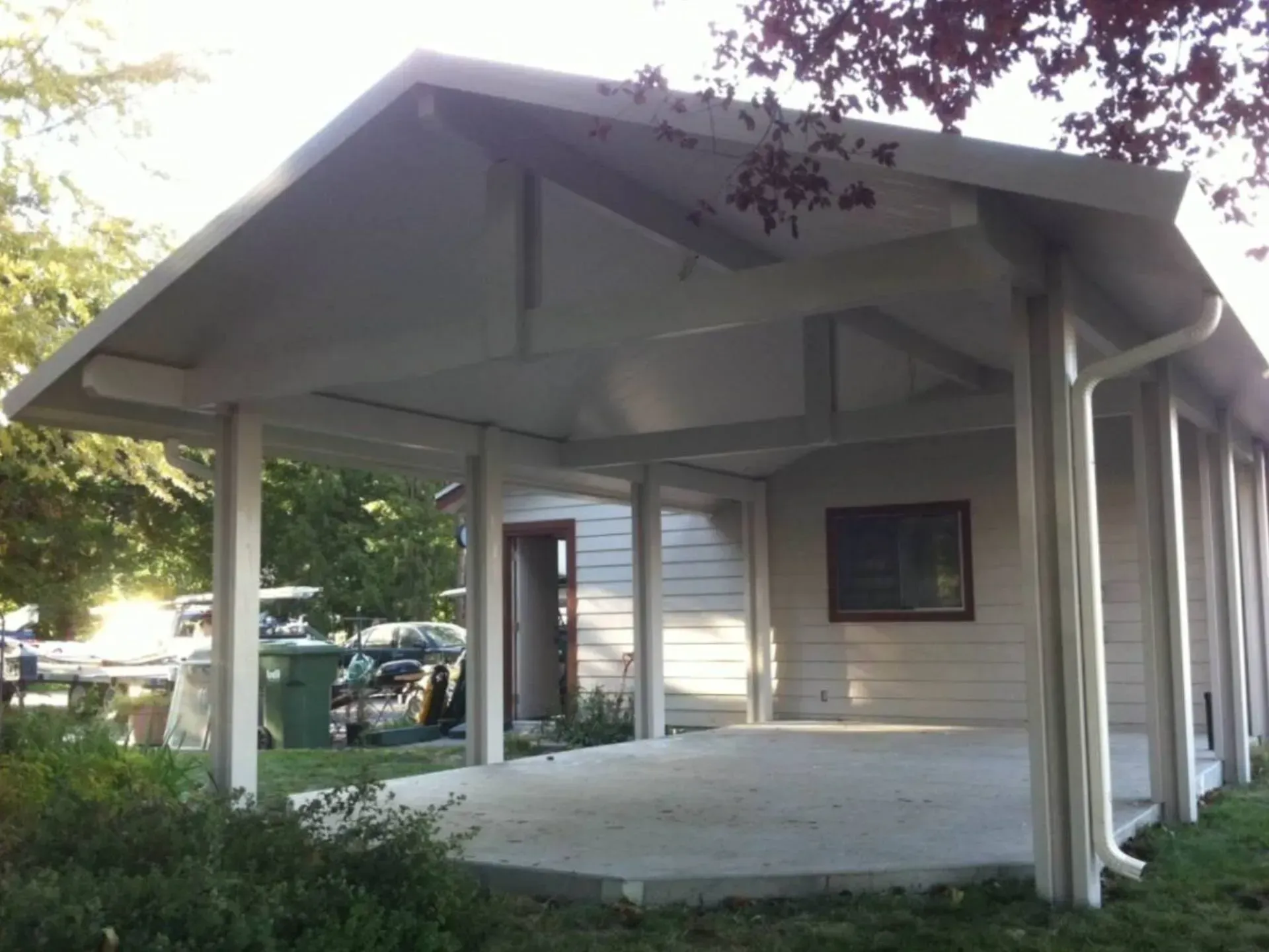 Small white pavilion with a peaked roof and open sides in a leafy outdoor setting