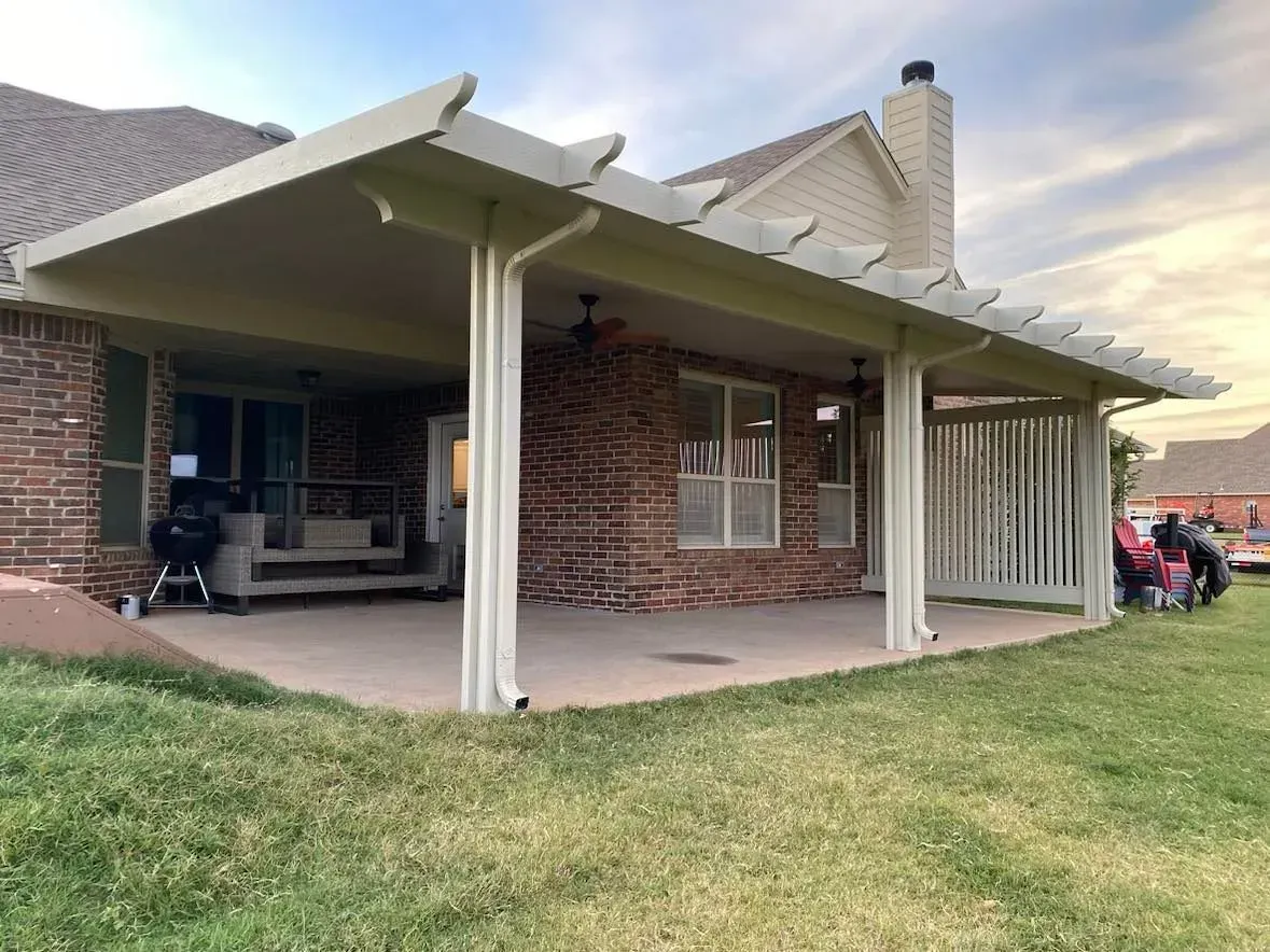 Brick house patio with white covered porch posts and a grassy yard