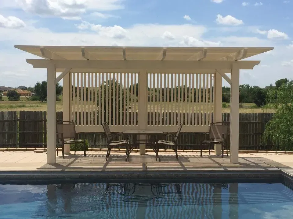 Backyard pool with a shaded pergola and lounge chairs by a fence and open field