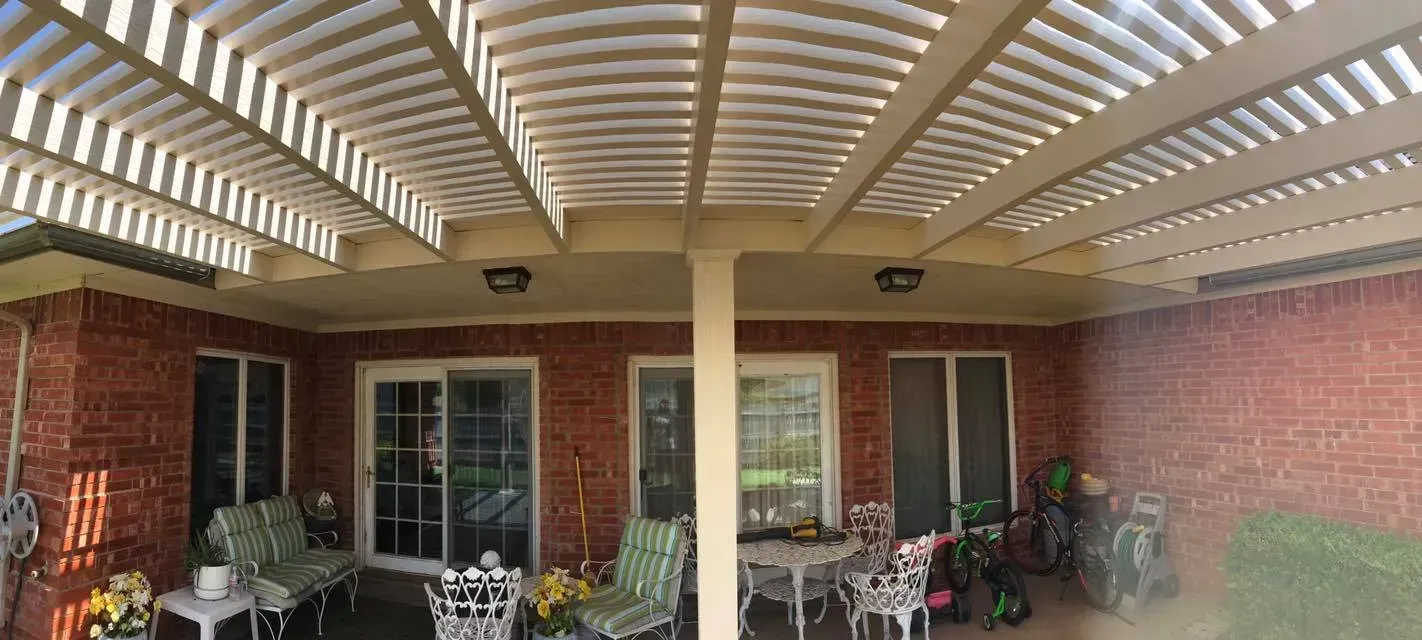 Covered brick patio with pergola, patio furniture, and potted plants outside a house