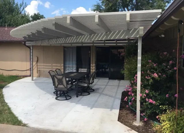 Back patio with pergola, patio table and chairs, sliding glass door, and flowering shrubs