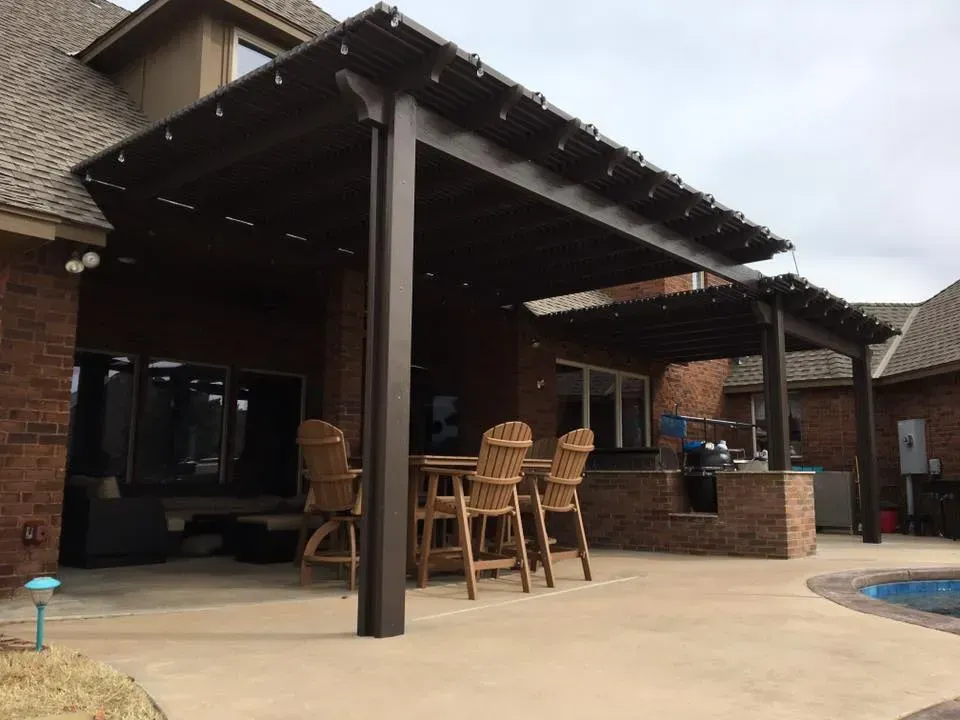 Covered backyard patio with wicker chairs, brick house, and a swimming pool on the right.