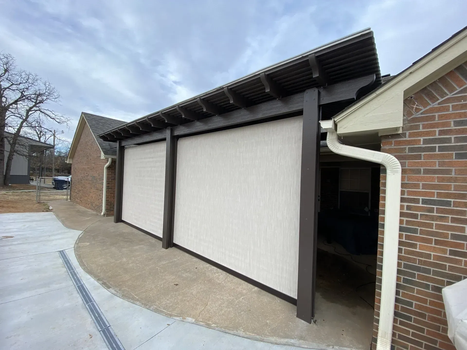 Outdoor brick building with large white sliding panels and a slanted roof next to a walkway