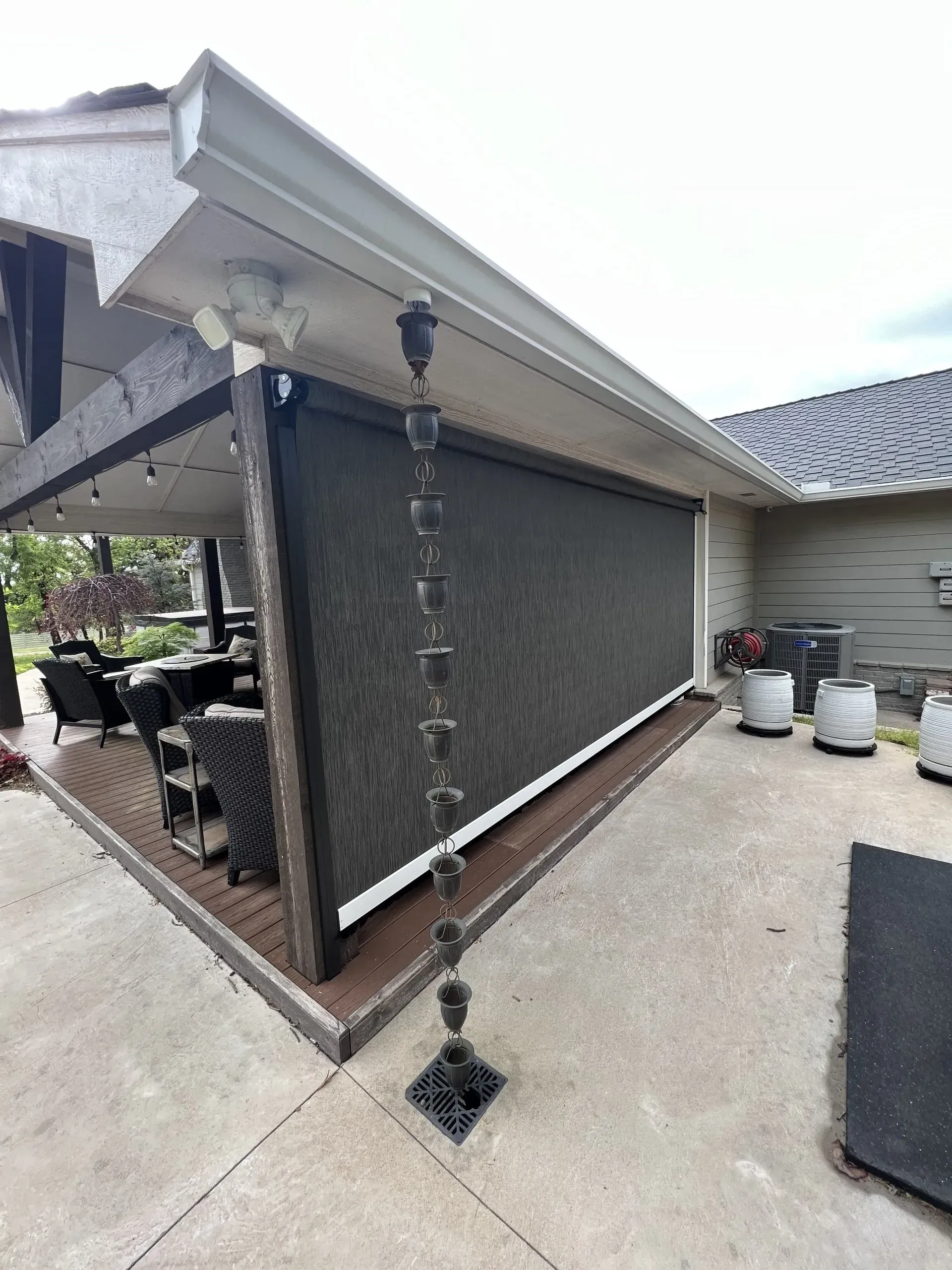 Backyard patio with a screened pergola, concrete floor, hanging chain rain curtain, and outdoor seating