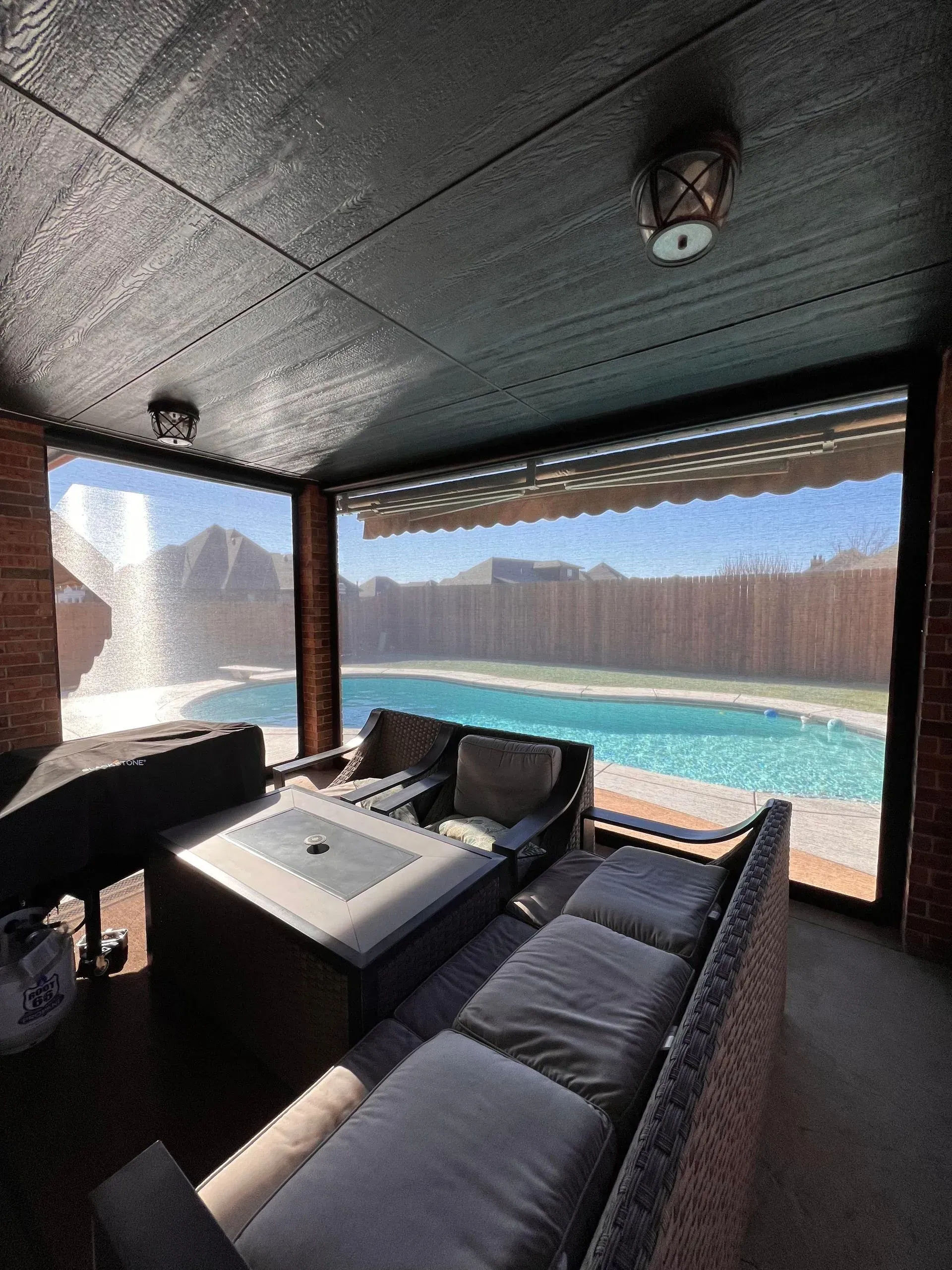 Covered patio with gray outdoor seating and a turquoise pool overlooking a canyon and mountains.