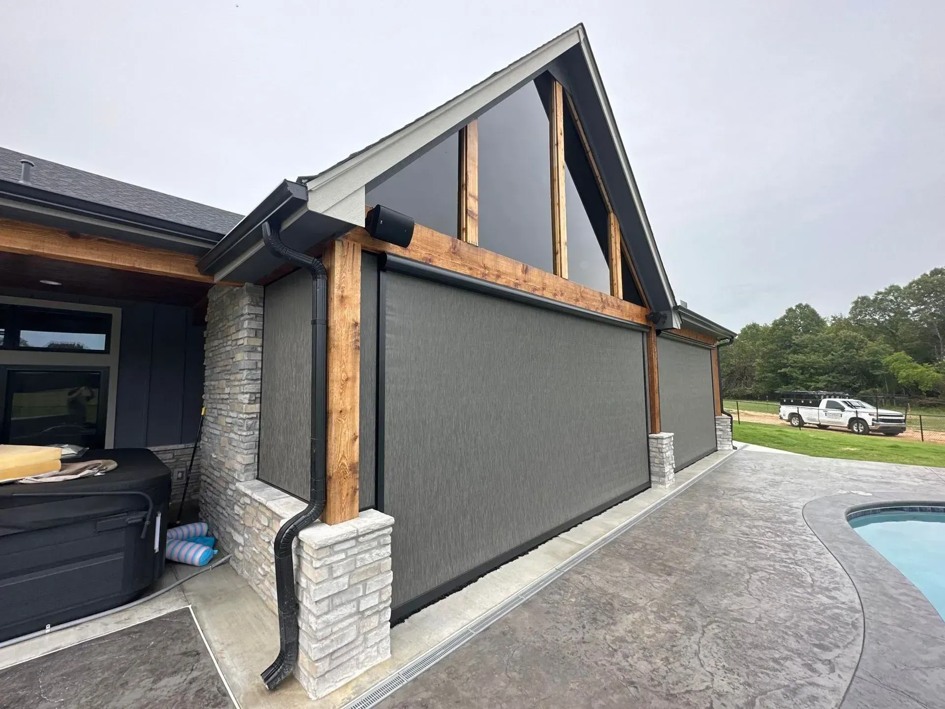 Modern house exterior with dark siding, stone columns, and a curved driveway under construction