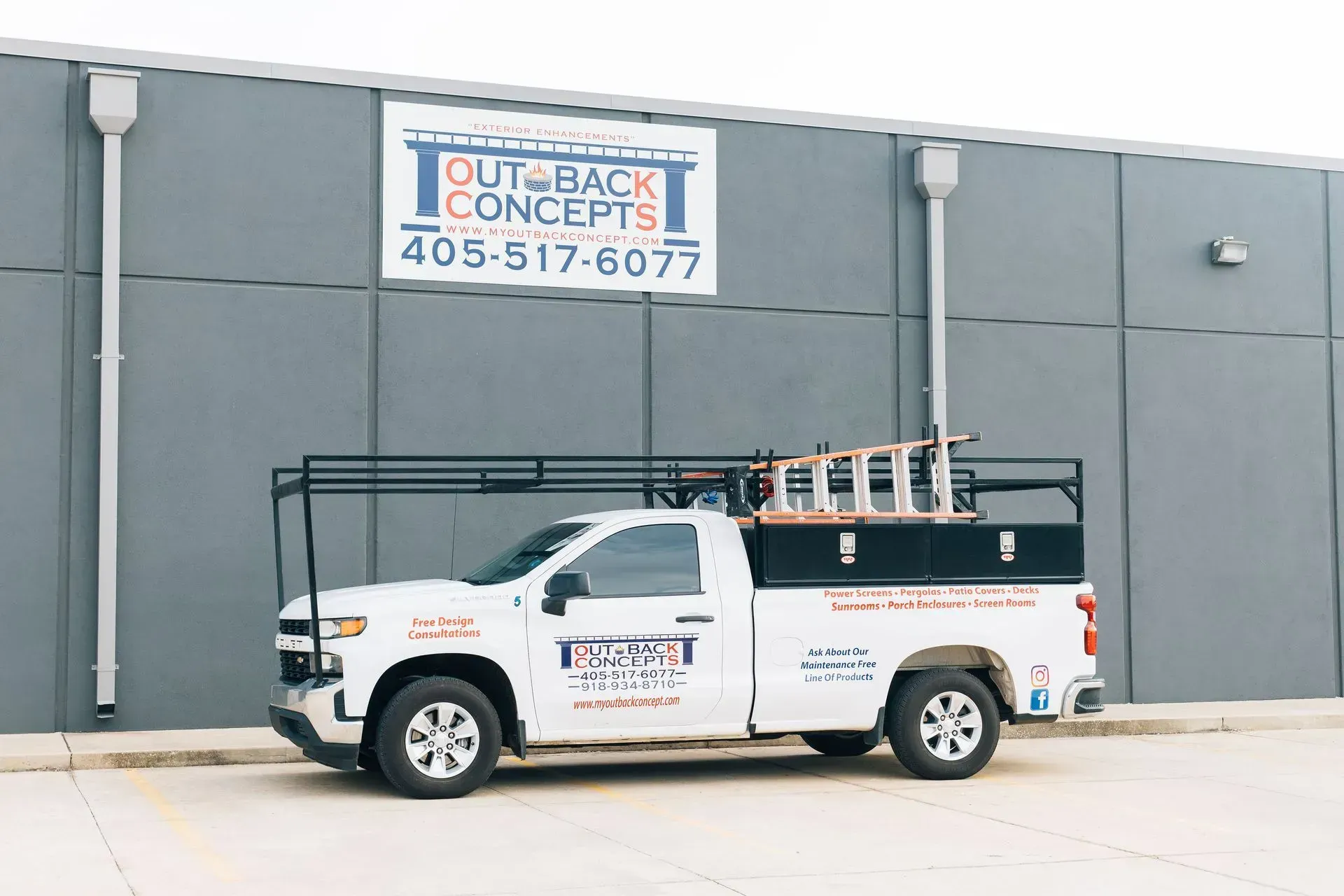 White utility truck parked beside a gray building with a 