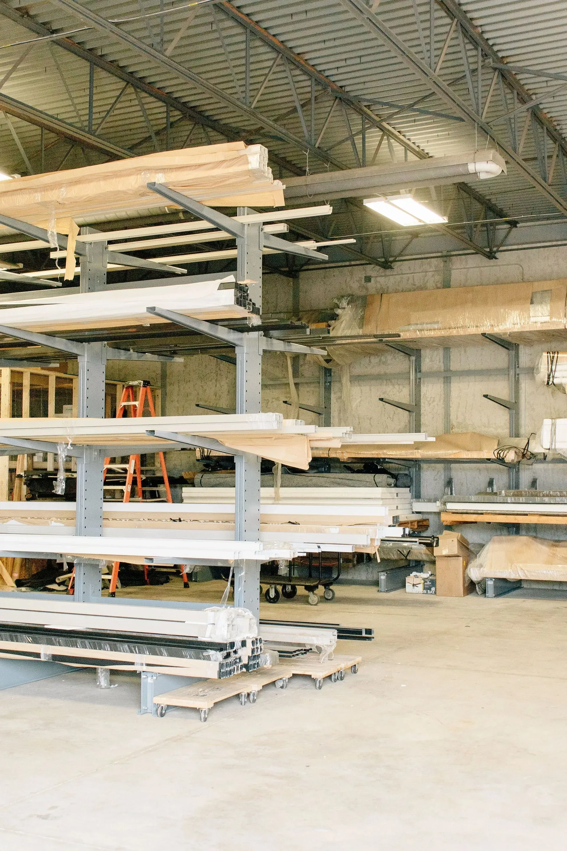 Warehouse shelving with long stacks of lumber and metal beams under a high ceiling
