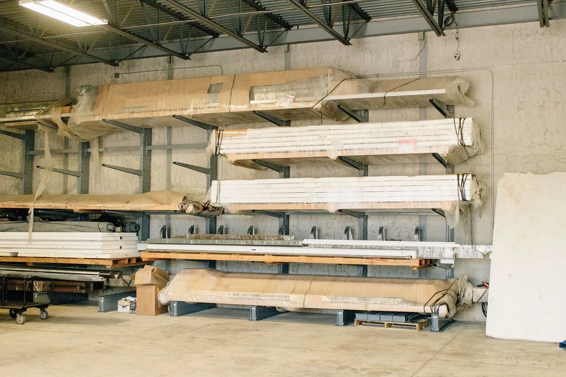 Stacks of lumber stored on metal racks inside a warehouse workshop.