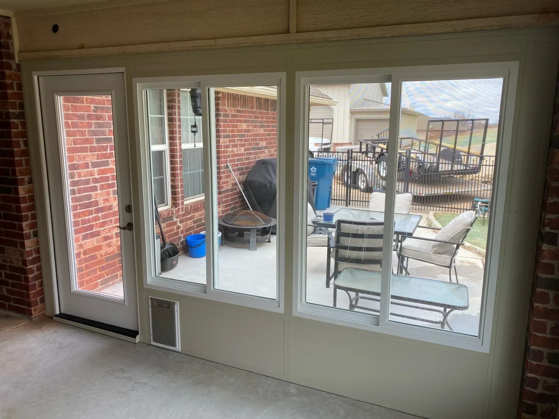 Patio room with large windows and a glass door overlooking outdoor furniture and a brick courtyard.