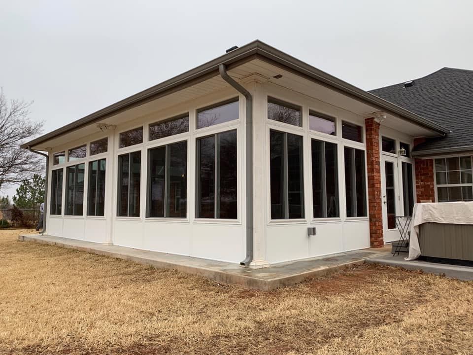 New white sunroom addition with large windows attached to a house