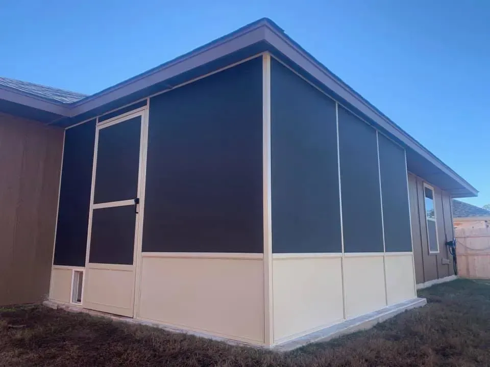 Screened porch with white trim and beige lower panels on a house under a blue sky.