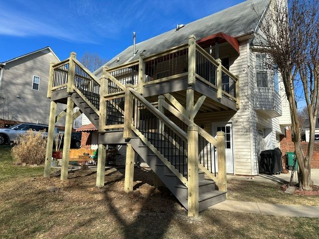 a wooden deck with stairs leading up to it is in front of a house .
