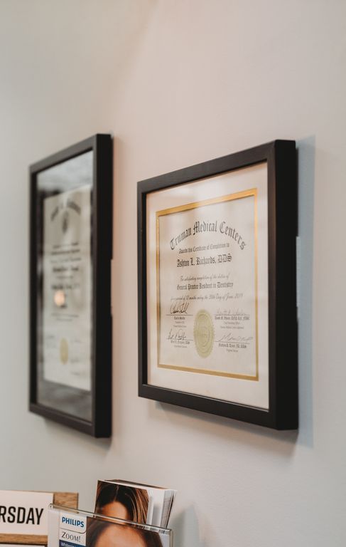 Framed diplomas on a white wall in a doctor's office.