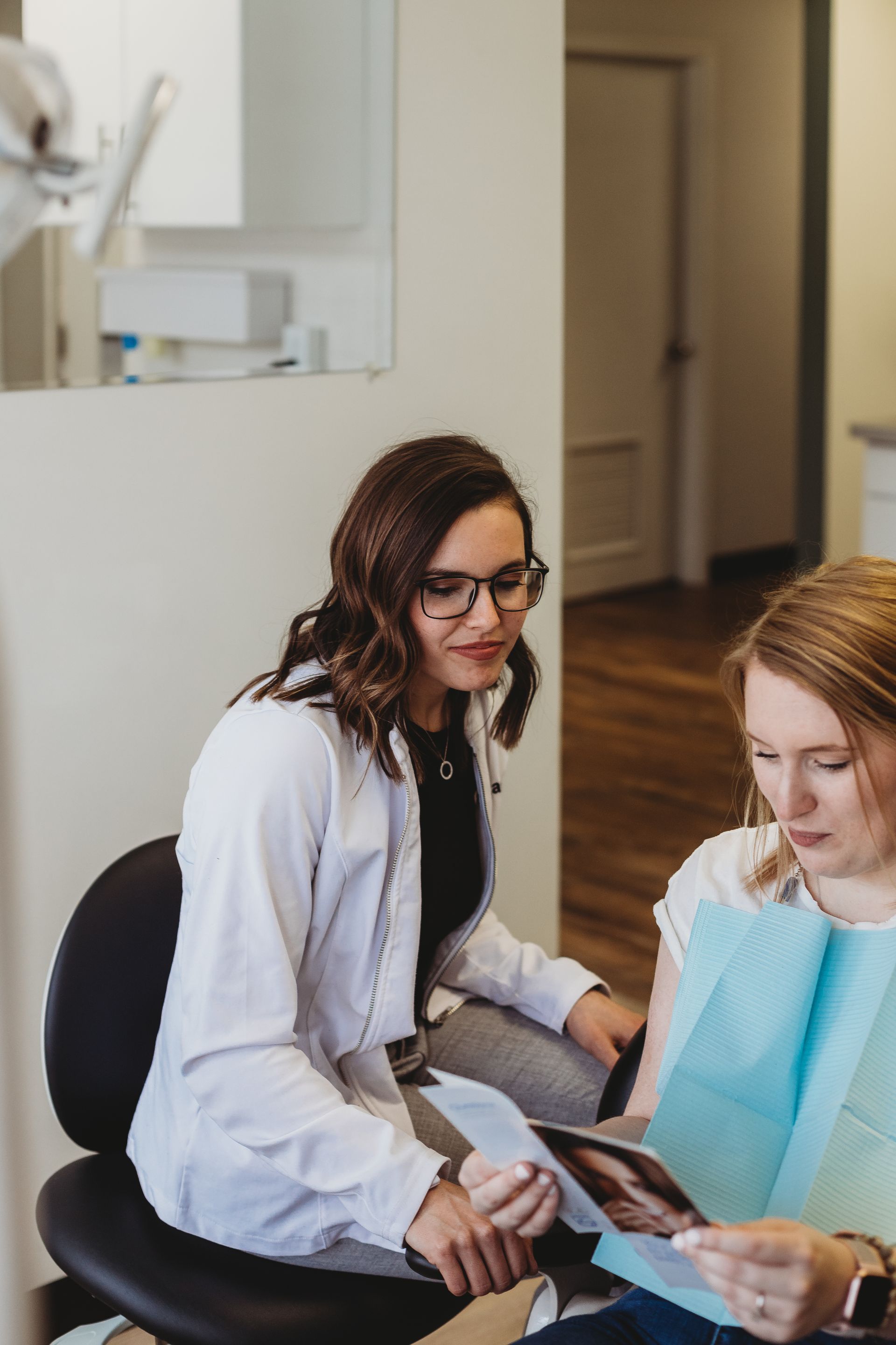 Dentist showing a patient dental images in a clinic setting. Both are looking at the pictures, smiling.