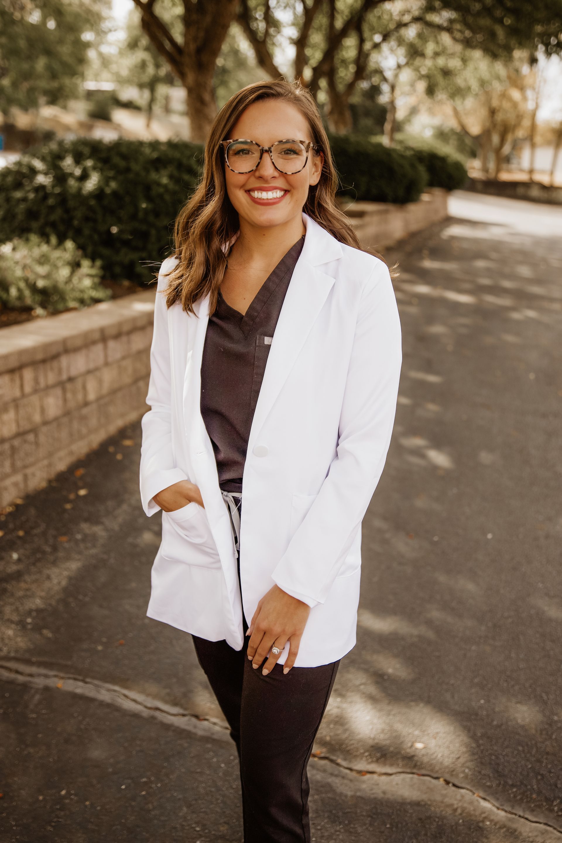 Woman in white coat, smiling, outdoors.