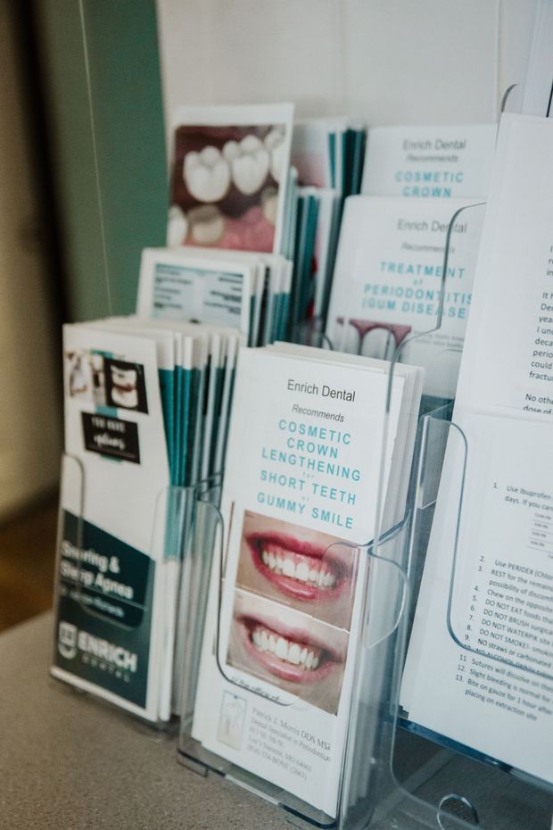 Brochures in a clear display rack at a dental office. Topics include cosmetic dentistry, dental implants, and smile makeovers.