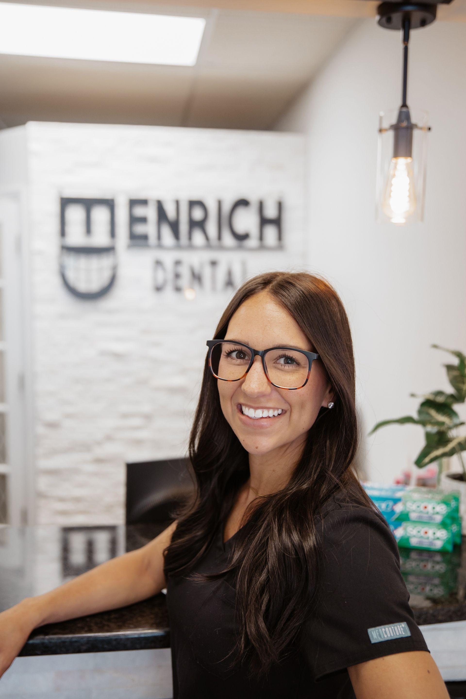 Woman at dental office reception, smiling. 