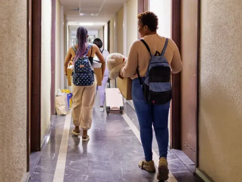 People moving boxes and belongings down a hallway.