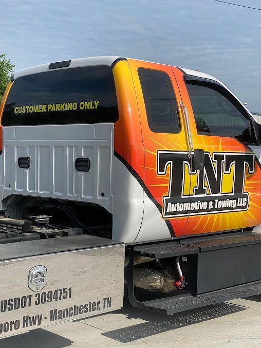TNT Customs tow truck with orange and yellow flame graphics and “CUSTOMER PARKING ONLY” on the cab